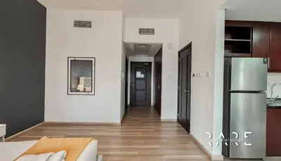 a kitchen with white walls and wooden floors and a refrigerator at Rare Holiday Homes - Mediterranean Cluster - Near Ibn Battuta Mall - Discovery Garden - Building# Med 79 - R203 in Dubai
