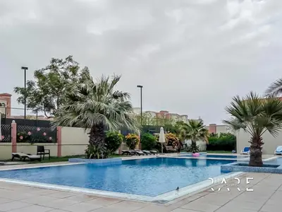 a swimming pool with palm trees in a resort at Rare Holiday Homes - Mediterranean Cluster - Near Metro - Discovery Garden - Building# Med 103 - RG07 in Dubai