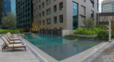 a hotel swimming pool with lounge chairs in front of a building at Downtown Studio - Cour Jardin in Dubai