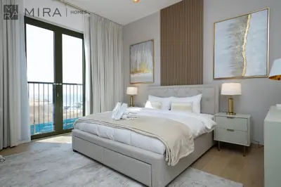 a bedroom with a large bed and a balcony at Mira Holiday Homes - Luxury 2 bedroom in Le Pont in Dubai