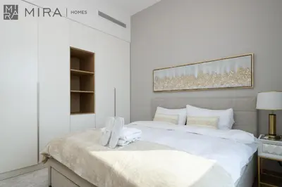a white bedroom with a large bed with white sheets at Mira Holiday Homes - Luxury 2 bedroom in Le Pont in Dubai