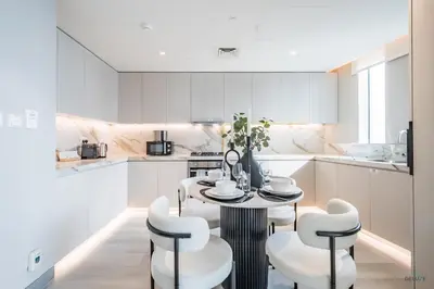 a white kitchen with a table and chairs at Waterfront Living 2BR Apartment in Marina Star, Dubai Marina by Deluxe Holiday Homes in Dubai