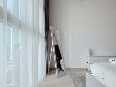 a white bedroom with a mirror and a bed at Rare Holiday Homes - Near Madame Tussauds - DEC Tower 1 - Dubai Marina - R2008 in Dubai