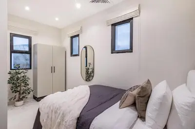a bedroom with a bed and a mirror and windows at Luxury Palm Villa with Beach Access -Rooftop Garden & Resort Style Pool by Exclusive Holiday Homes in Dubai