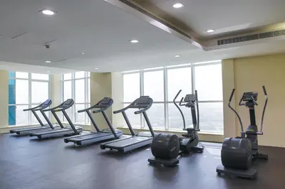a row of treadmills in a gym with windows at Blueground Duja Tower City View pool gym DXB-1108 in Dubai