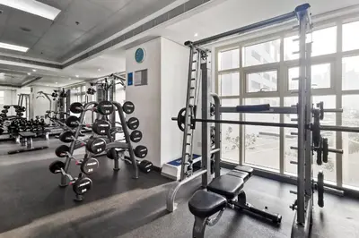 a gym with several tread machines and a window at Blueground The Royal Oceanic pool gym DXB-1152 in Dubai