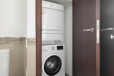 a washer and dryer in a bathroom with a door at Blueground DIFC Burj K view pool fitness DXB-1535 in Dubai