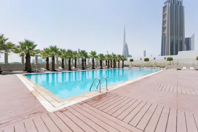 a large swimming pool with palm trees and buildings at Blueground DIFC Burj K view pool fitness DXB-1535 in Dubai
