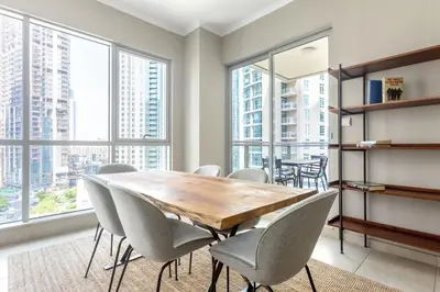 a dining room with a table and chairs and windows at Blueground Downtown B Khalifa view pool DXB-645 in Dubai