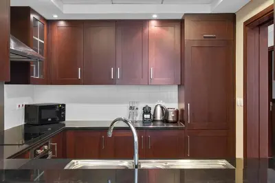 a kitchen with wooden cabinets and a sink at BellaVista - 29 Boulevard 2 Bedroom Downtown Fountain View in Dubai