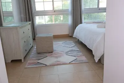a bedroom with a bed and a dresser and windows at Fully Furnished Garden Villa 2 Bedroom in Dubai
