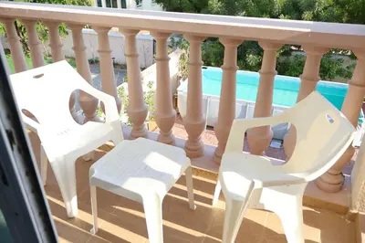 two white chairs on a balcony with a pool at Fully Furnished Garden Villa 2 Bedroom in Dubai