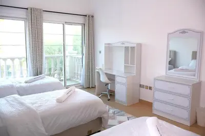 a bedroom with two beds and a desk and a window at Fully Furnished Garden Villa 2 Bedroom in Dubai