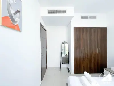 a living room with a wooden door and white walls at Luxury 3-Bedroom Duplex in Damac Hills & balcony in Dubai