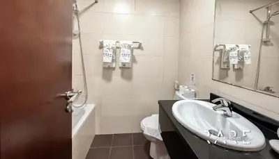 a bathroom with a sink and a toilet and a mirror at Rare Holiday Homes - Dubai Sports City - Elite Residence - R1303 in Dubai