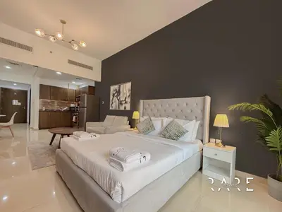 a bedroom with a large bed and a living room at Rare Holiday Homes - Jumeirah Village Circle - Near Circle Mall - Botanica Tower - R105 in Dubai