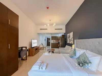 a bedroom with a large bed and a living room at Rare Holiday Homes - Jumeirah Village Circle - Near Circle Mall - Botanica Tower - R105 in Dubai