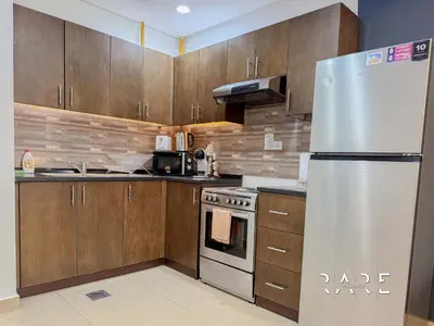 a kitchen with wooden cabinets and a stainless steel refrigerator at Rare Holiday Homes - Jumeirah Village Circle - Near Circle Mall - Botanica Tower - R105 in Dubai
