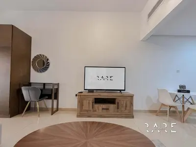 a living room with a television on a wooden table at Rare Holiday Homes - Jumeirah Village Circle - Near Circle Mall - Botanica Tower - R105 in Dubai