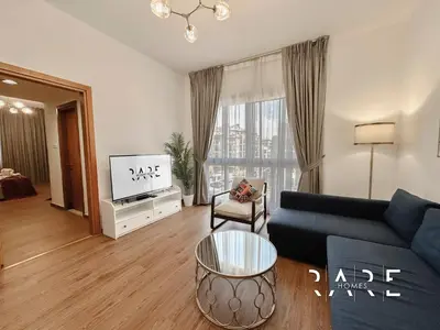 a living room with a couch and a tv at Rare Holiday Homes - Near Circle Mall - Lavender 1 - R309 - Jumeirah Village Circle in Dubai