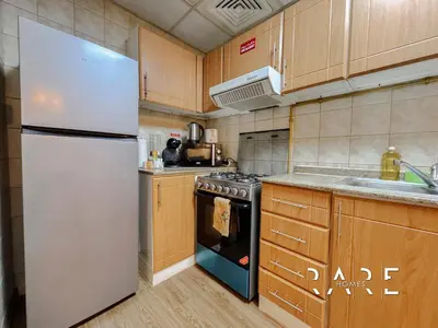 a kitchen with a white refrigerator and a stove at Rare Holiday Homes - Near Circle Mall - Lavender 1 - R309 - Jumeirah Village Circle in Dubai