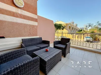 a patio with wicker furniture and a table and chairs at Rare Holiday Homes - Near Miracle Garden - Lavender 2 - RG012 - Jumeirah Village Circle in Dubai