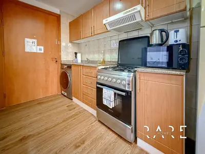 a kitchen with a stove and a microwave at Rare Holiday Homes - Near Miracle Garden - Lavender 2 - RG012 - Jumeirah Village Circle in Dubai