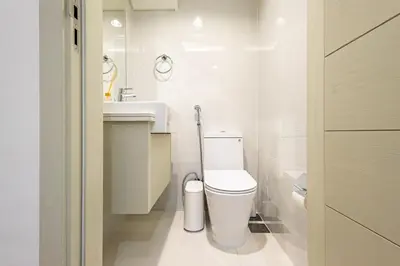 a white bathroom with a toilet and a sink at Luxury 3BR 2storey Villa with Garden in Damac Hills in Dubai