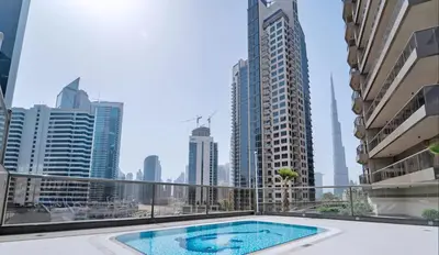 a balcony with a swimming pool in the middle of a city at Close to Downtown - New 1 bedroom with parking in Dubai