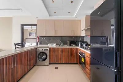 a kitchen with wooden cabinets and a washer and dryer at Close to Downtown - New 1 bedroom with parking in Dubai