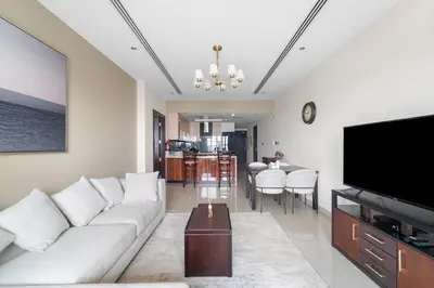 a living room with a white couch and a television at Close to Downtown - New 1 bedroom with parking in Dubai