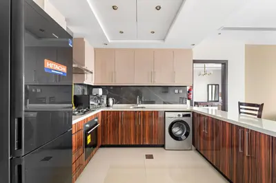 a kitchen with wooden cabinets and a washer and dryer at Big 1 bedroom close to Downtown in Dubai