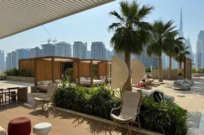 a patio with chairs and tables and palm trees at Stylish Studio in Upside Living with Top Amenities in Dubai