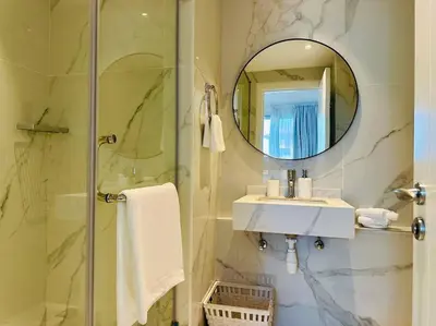a bathroom with a shower and a sink and a mirror at Manzil - 2BR Home with Waterfront Views in Palm in Dubai