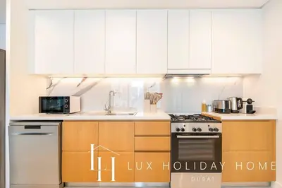 a kitchen with white cabinets and a stove top oven at LUX The JBR Garden View Suite in Dubai