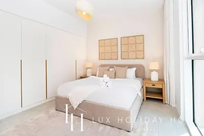 a white bedroom with a large bed and two lamps at LUX The JBR Garden View Suite in Dubai