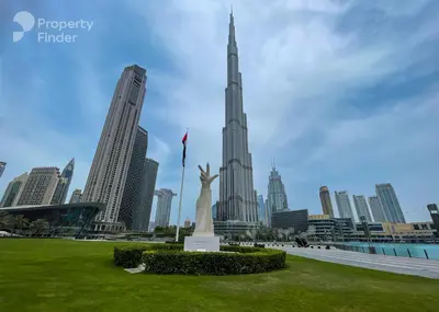 a statue in a park in front of a city at Spacious 1BR - Elite Downtown Residence - Short Walk to Burj & Dubai Mall in Dubai