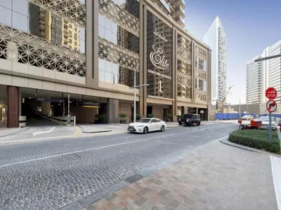 a white car driving down a street in front of a building at Spacious 1BR - Elite Downtown Residence - Short Walk to Burj & Dubai Mall in Dubai