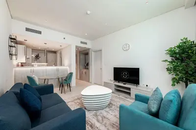 a living room with blue couches and a kitchen at Seven Palms in Dubai