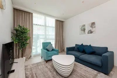 a living room with a blue couch and two chairs at Seven Palms in Dubai