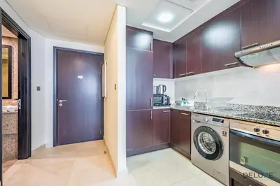 a kitchen with wooden cabinets and a washer and dryer at Exclusive Studio at Sky Gardens, DIFC by Deluxe Holiday Homes in Dubai