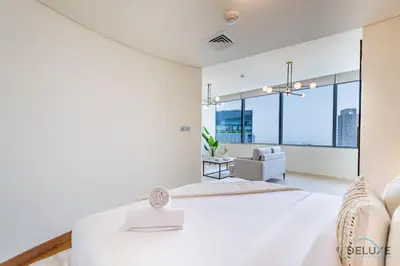 a white bedroom with a large bed and a couch at Exclusive Studio at Sky Gardens, DIFC by Deluxe Holiday Homes in Dubai
