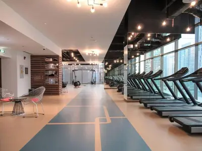 a gym with rows of treadmills and chairs at Stylish 3BR Apartment in Dubai Marina with Pool, Gym, and Views in Dubai