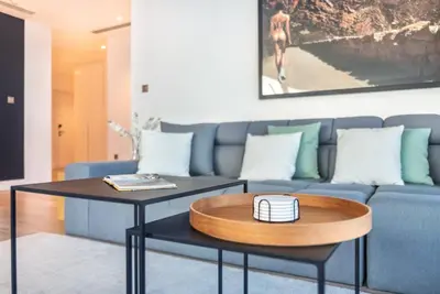 a living room with a blue couch and a table at Stylish 3BR Apartment in Dubai Marina with Pool, Gym, and Views in Dubai