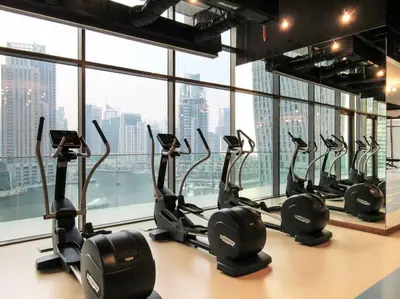 a row of treadmills in a gym in front of a window at Stylish 3BR Apartment in Dubai Marina with Pool, Gym, and Views in Dubai