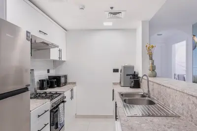a white kitchen with a sink and a stove at Comfy 1BR Marina Living Steps from Marina Walk in Dubai