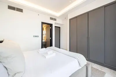 a bedroom with a white bed and a large cabinet at Upscale 2BR with Private Terrace & Pool View in Dubai