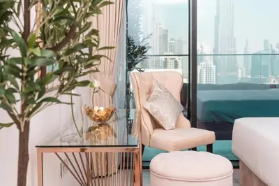 a living room with a chair and a glass table at Elite Royal Apartment - Sky Series - Panoramic Burj Khalifa, Skyline & Fountain View - Admiral in Dubai