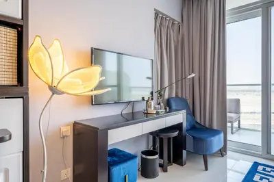 a room with a desk with a tv and a blue chair at Stylish Studio with Pool View & Free Parking in Dubai