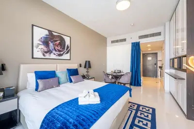 a bedroom with a large bed with blue pillows at Stylish Studio with Pool View & Free Parking in Dubai